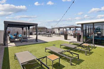 A sunny day on the tropical deck with 
 an outdoor seating area and cabanas at Alameda West Apartments in Miami, FL